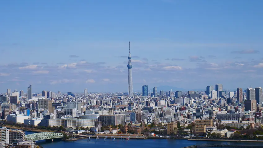 Aerial view of Tokyo skyline, featuring the iconic Tokyo Skytree under a clear blue sky.