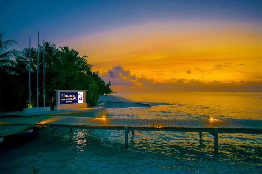 Golden hour view of a wooden deck by the sea in Maldives, with stunning sunset colors.