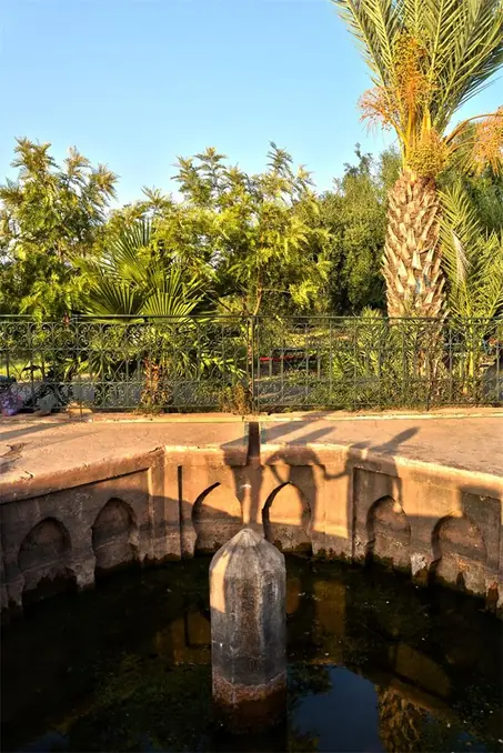 Sunlit garden with a traditional fountain in Marrakech, Morocco.