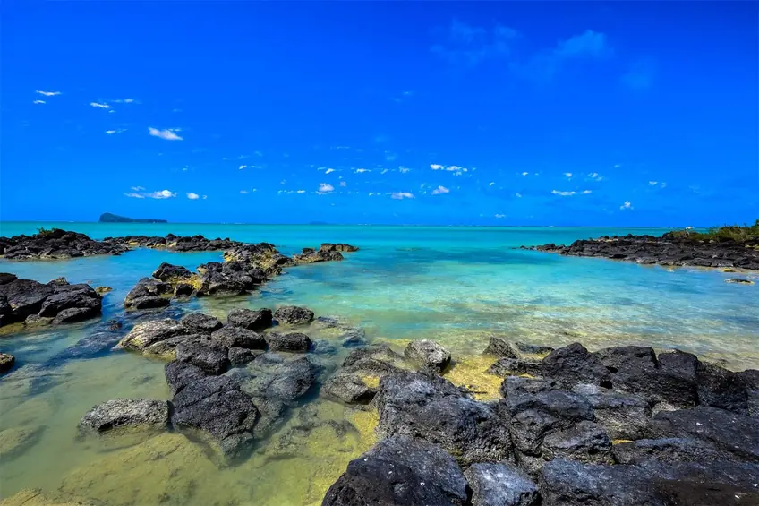 Beautiful coastal scene in Mauritius with clear turquoise waters and rocky shores.