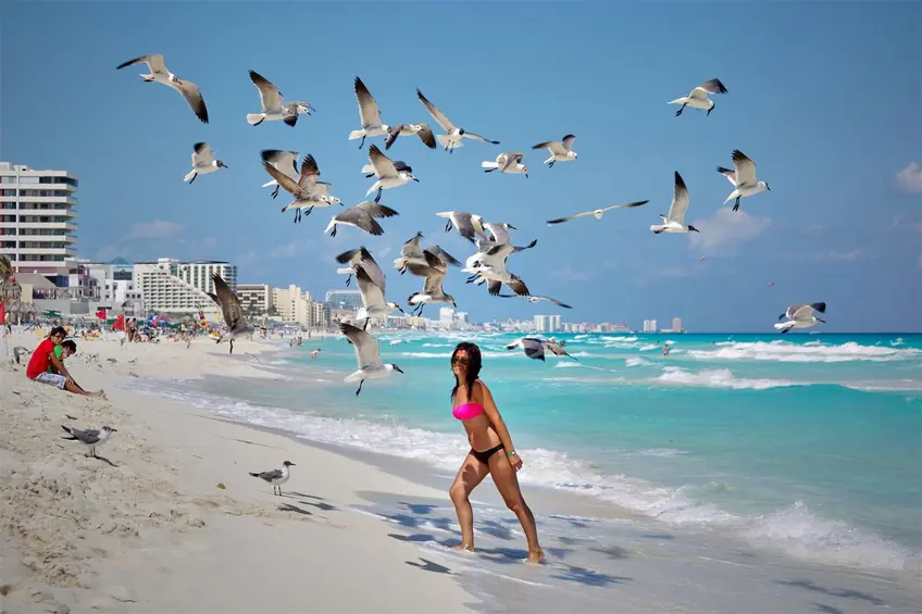 Woman on Cancun beach enjoying the summer surrounded by seagulls.