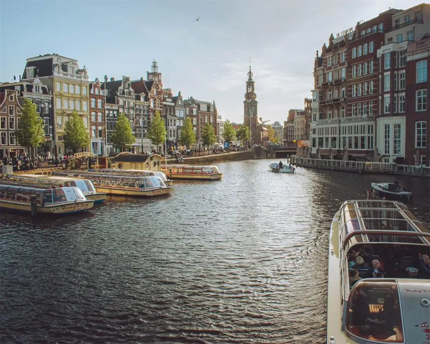 Charming view of Amsterdam's canals with tour boats and historic buildings, capturing the essence of the city.