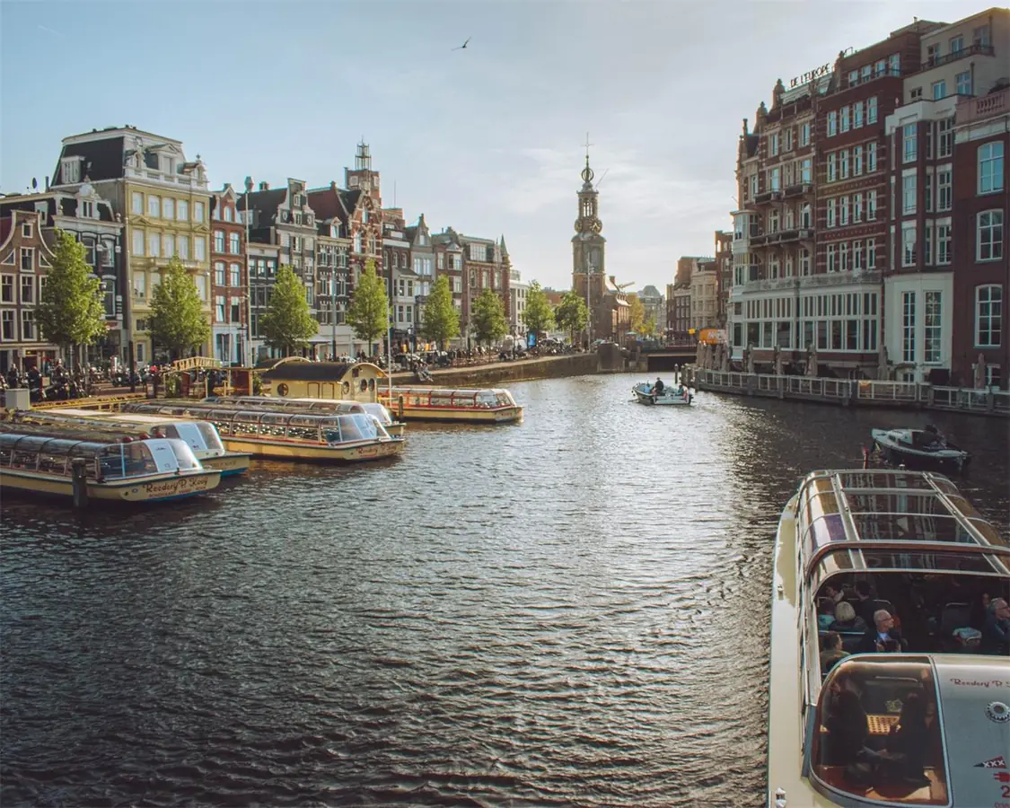 Charming view of Amsterdam's canals with tour boats and historic buildings, capturing the essence of the city.