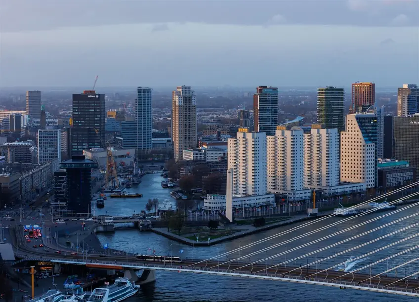 A breathtaking view of Rotterdam's modern skyline and Erasmus Bridge at dusk.