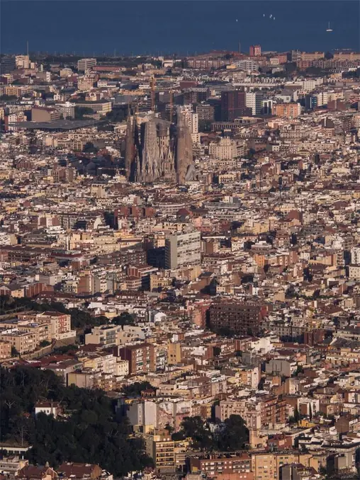 Aerial view of the iconic Sagrada Familia amidst Barcelona's dense cityscape.