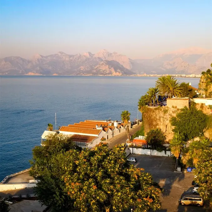 Aerial view of Antalya coast with mountains, sea, and clear sky.