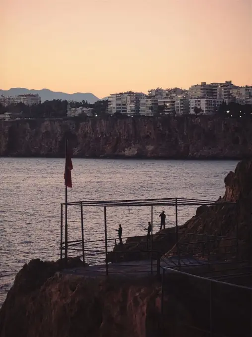 Dramatic sunset at Antalya's coastline with cliffs and sea view.