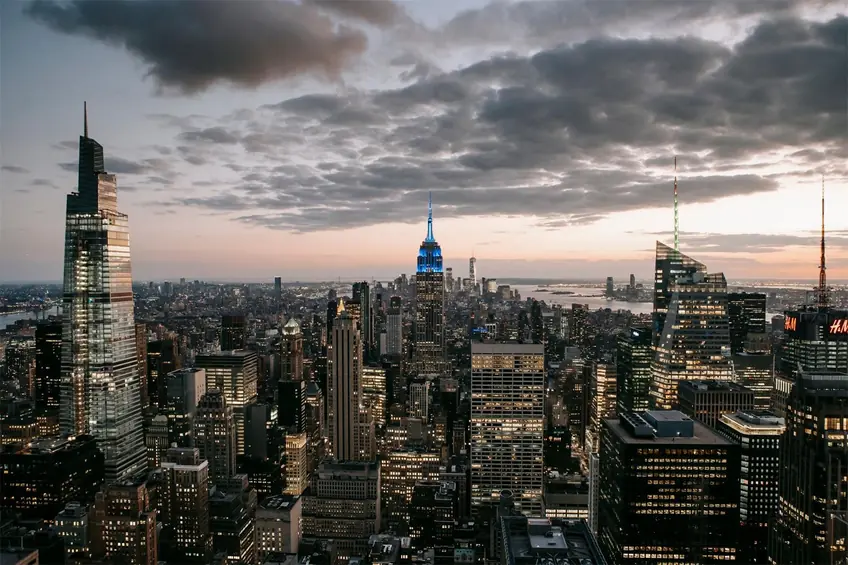Modern skyscraper exteriors against endless ocean under cloudy sky in New York City at sundown