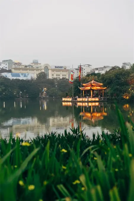 Beautiful pavilion reflecting in Hoan Kiem Lake in Hanoi, showcasing Vietnamese architecture.