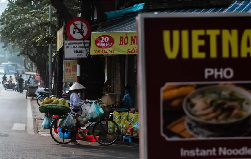 A vibrant scene of a Vietnamese street vendor with produce-laden bicycle in Hanoi.