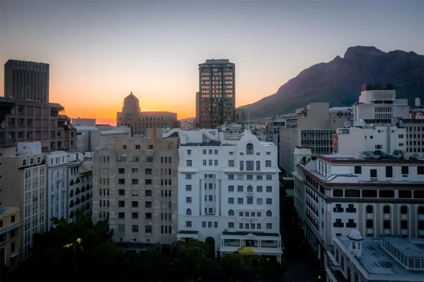 View of Cape Town's skyline at sunset with Table Mountain in the background. Vibrant, urban cityscape.