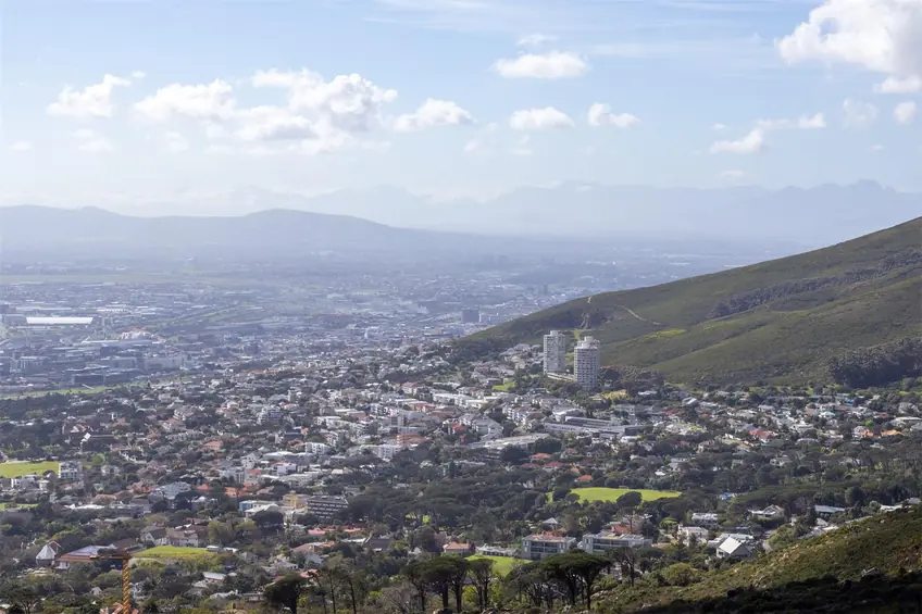 Scenic aerial view of Cape Town cityscape with Table Mountain in the background under a clear blue sky.